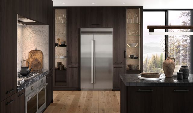 front view of a rustic luxury kitchen with dark brown cabinets and a sub-zero stainless steel refrigerator built in